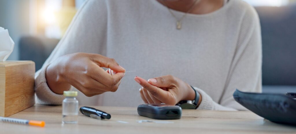 Primer plano de una persona realizando prueba de glucosa en casa, rodeada de insumos médicos, ilustrando el control glucémico en diabetes tipo 2.