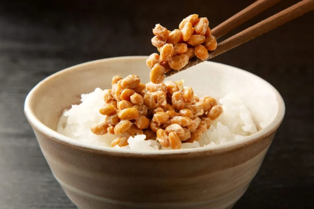 Tazón de arroz con nattō, alimento fermentado japonés reconocido como fuente natural de vitamina K₂ altamente biodisponible para la salud ósea y cardiovascular.