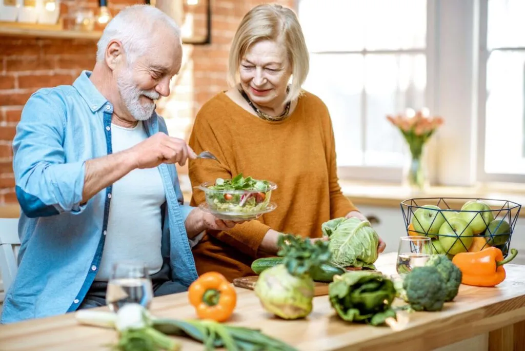 Adultos mayores preparando ensalada y vegetales frescos como parte de cambios nutrición para más energía y bienestar