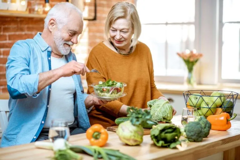 Adultos mayores preparando ensalada y vegetales frescos como parte de cambios nutrición para más energía y bienestar