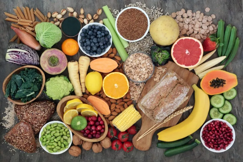 Variedad de alimentos ricos en fibra como frutas, verduras, granos integrales y semillas, ideales para una dieta equilibrada y salud digestiva.