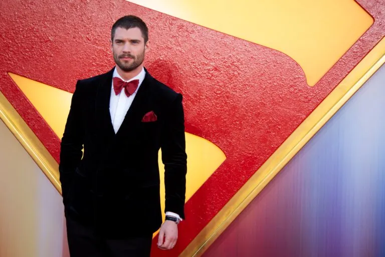 David Corenswet en alfombra roja frente al logo de Superman, mostrando el resultado de su plan de nutrición y entrenamiento especializado.