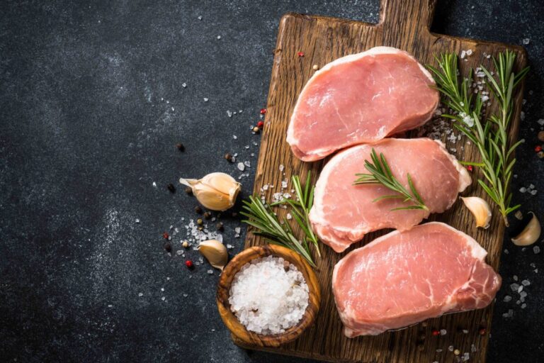 Carne de puerco magra lista para cocinarse y ser servida con vegetales frescos en plato equilibrado saludable según Profeco