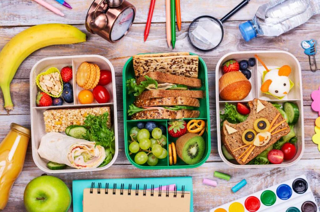 Lonchera escolar con cereales integrales, frutas, verduras y proteínas saludables presentada de forma colorida y atractiva