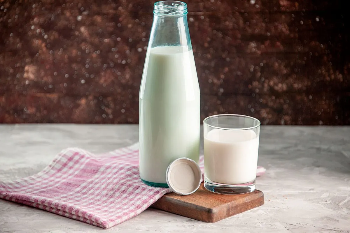 Impacto nutricional de la leche mostrado en un vaso de leche junto a frutas y cereales saludables