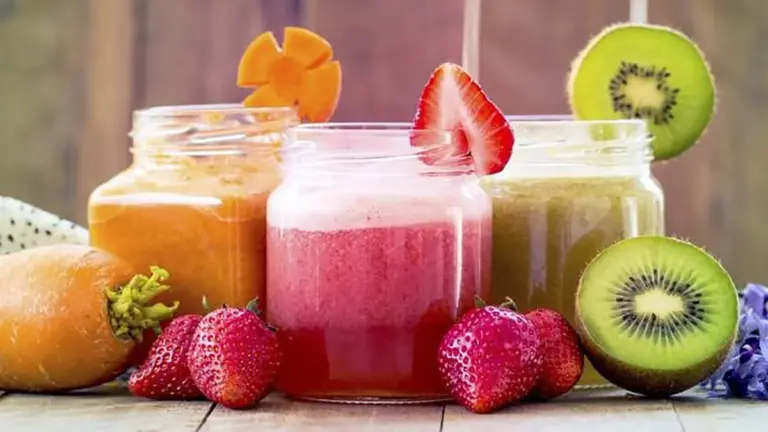 Vasos con jugos détox verdes y rojos preparados con frutas y verduras frescas sobre una mesa limpia y moderna
