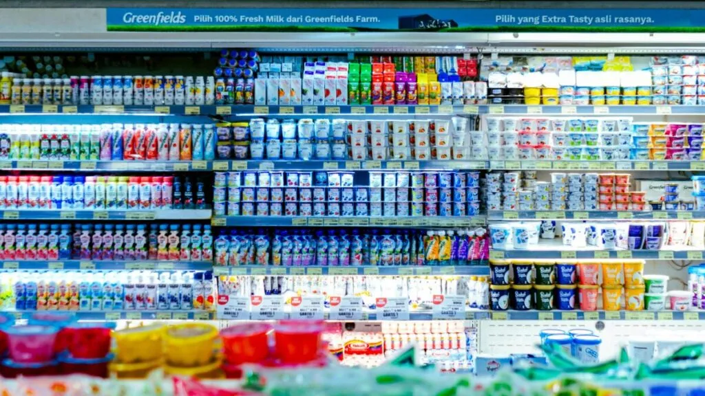 Alimentos en supermercado con etiquetas visibles que ilustran el control de aditivos en alimentos y colorantes seguros para consumo