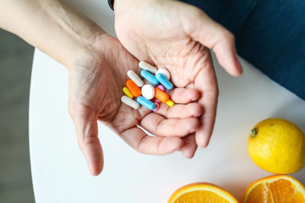 Frutas frescas y cápsulas de multivitamínicos en mesa, representando la importancia de una dieta equilibrada.
