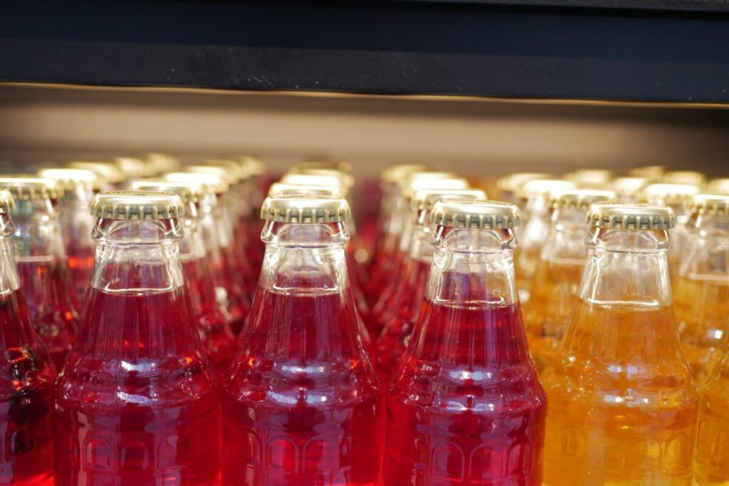 Botellas de vidrio con refrescos de distintos colores que ilustran cómo la regulación también impacta a productores pequeños y artesanales.