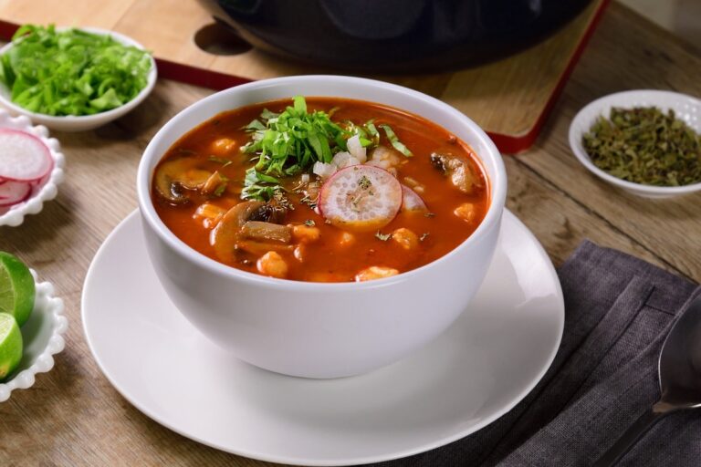 azón de pozole vegetariano con hongos desmenuzados y guarniciones frescas como rábanos y limón en mesa mexicana festiva
