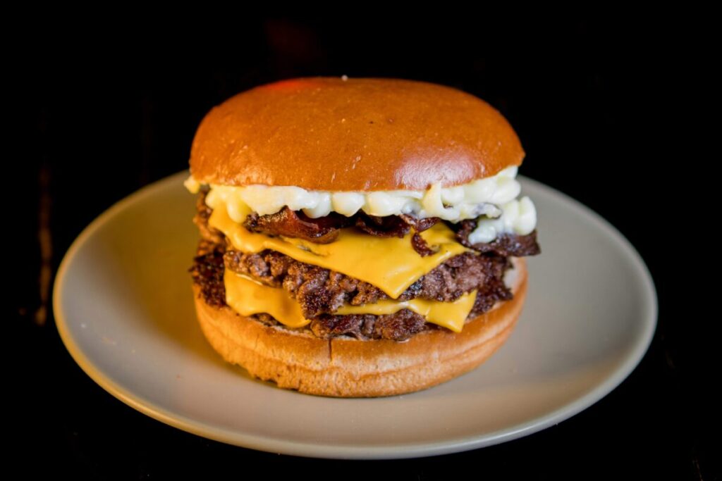 Persona comiendo comida rápida con expresión preocupada y elementos visuales que representan inflamación intestinal