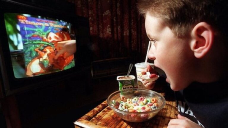 Niño frente a la televisión durante una comida, ilustrando el impacto en la nutrición infantil