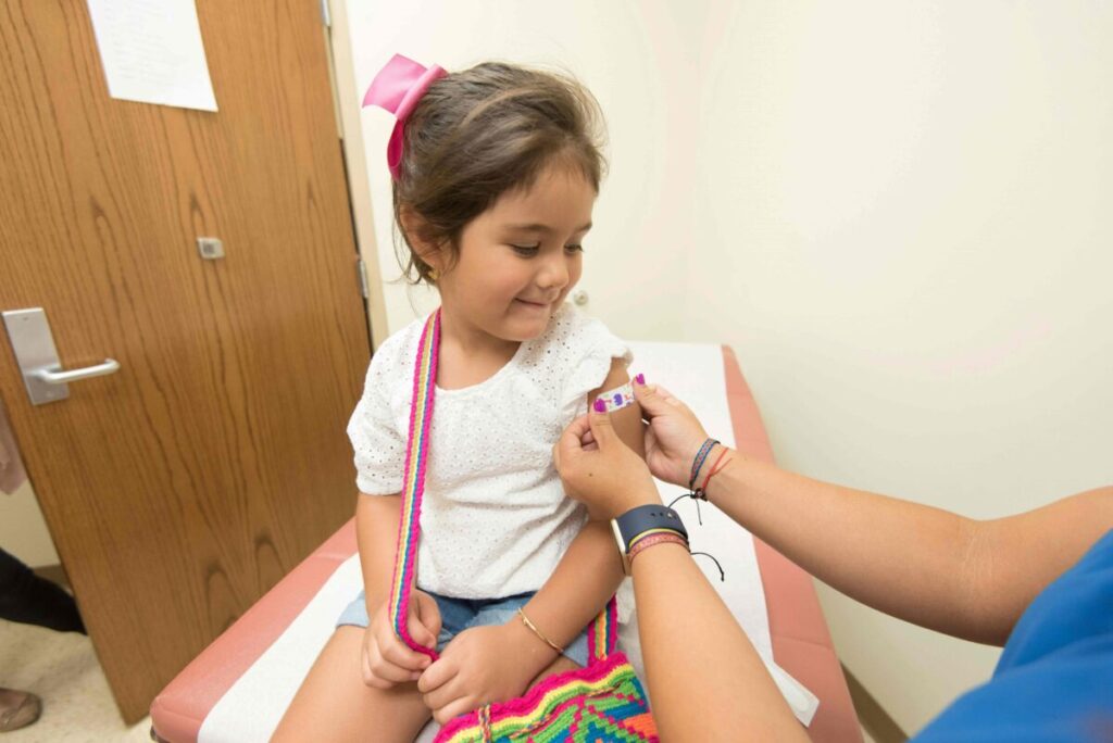 Niña recibiendo vacuna para prevenir la polio en centro de salud, protección contra enfermedades infecciosas