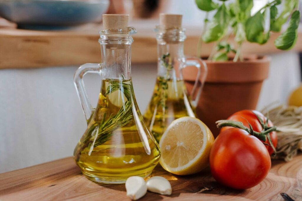 Botella de aceite de oliva sobre una mesa con alimentos frescos como tomate y pan integral