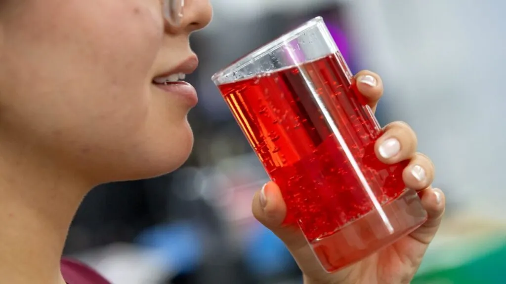 Mesa con dulces y bebidas con colorante rojo 3 junto a frutas naturales que simbolizan alternativas saludables