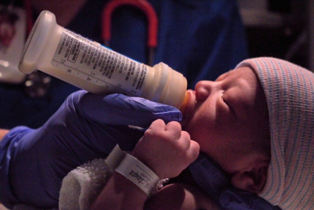 Enfermera alimenta a bebé prematuro en incubadora, parte del cuidado de nutrición neonatal en Uruguay