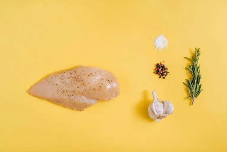 Persona cocinando pollo crudo con medidas de higiene alimentaria para evitar bacterias peligrosas.