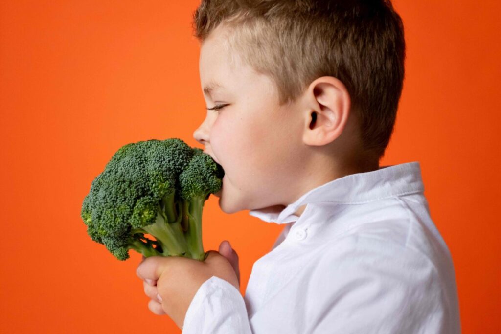 Niño sonriente comiendo frutas, promoviendo la nutrición infantil saludable