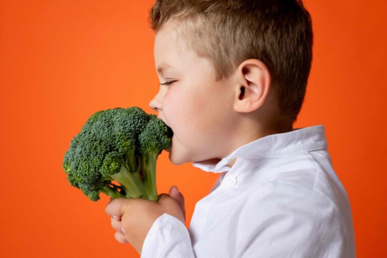 Niño sonriente comiendo frutas, promoviendo la nutrición infantil saludable