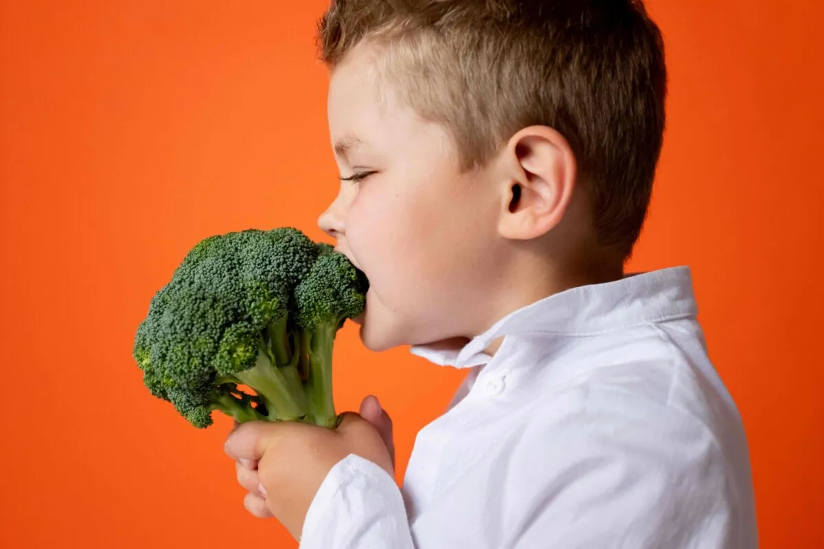 Niño sonriente comiendo frutas, promoviendo la nutrición infantil saludable