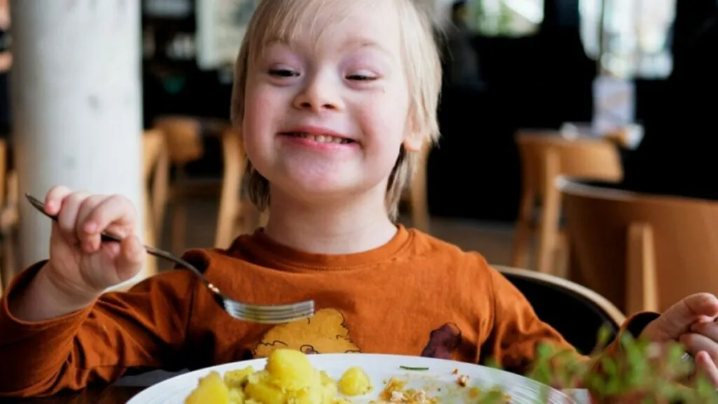 Persona con síndrome de Down comiendo frutas y verduras como parte de una alimentación equilibrada