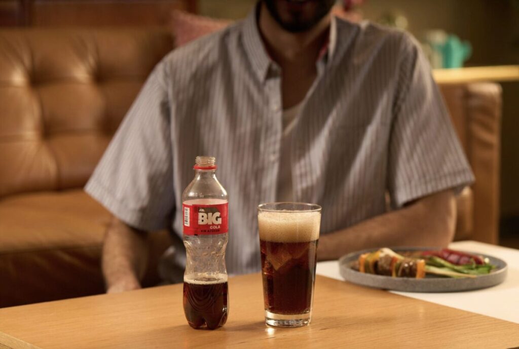 Botella de Big Cola junto a platillos tradicionales mexicanos.