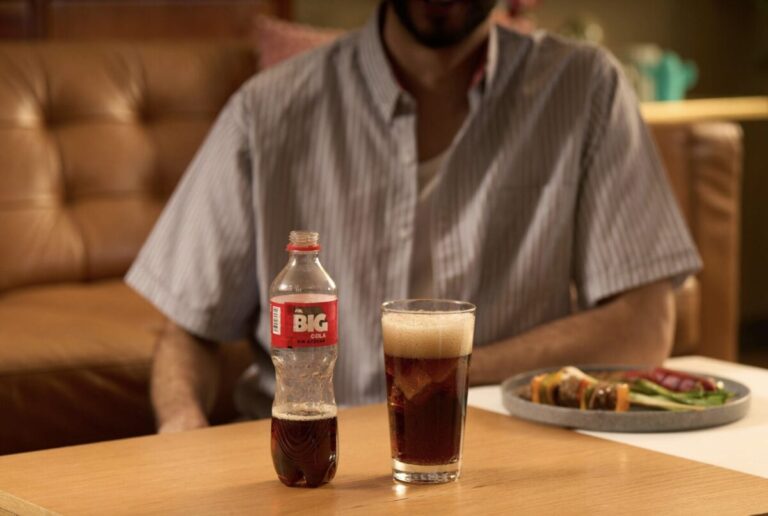 Botella de Big Cola junto a platillos tradicionales mexicanos.