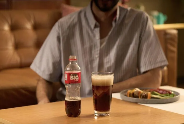 Botella de Big Cola junto a platillos tradicionales mexicanos.