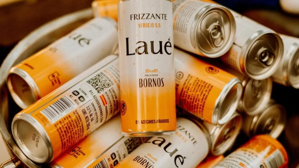 Latas de Laué Frizzante en primer plano dentro de un bowl metálico, mostrando información del producto y su presentación con 0% azúcar añadida.