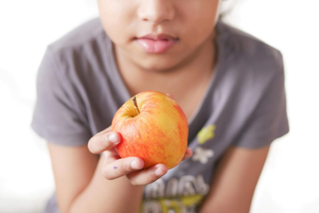 Niño sonriente eligiendo frutas para una lonchera saludable, símbolo de buena nutrición infantil