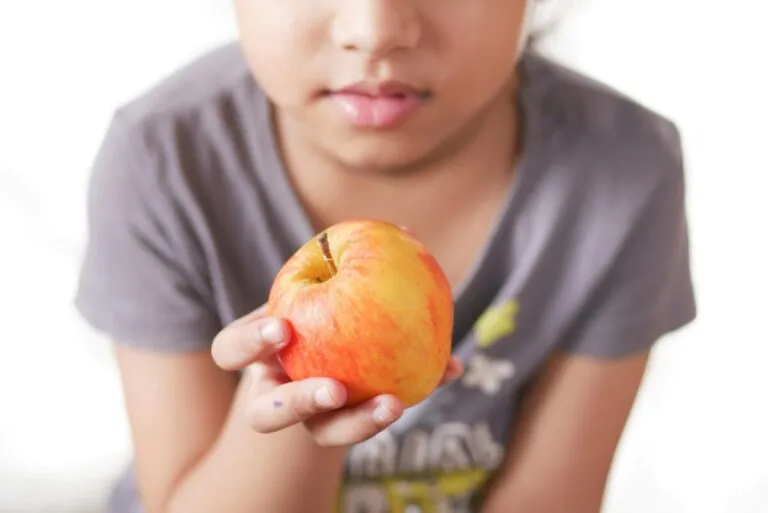 Niño sonriente eligiendo frutas para una lonchera saludable, símbolo de buena nutrición infantil