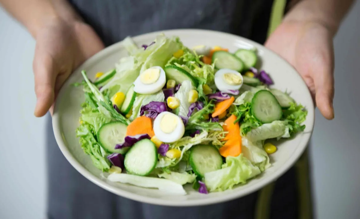 Mujer sosteniendo un bowl con vegetales crudos frente a su abdomen para aliviar el estreñimiento