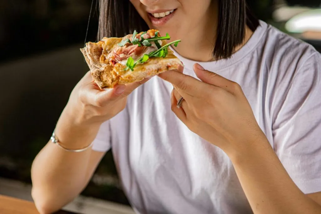 Mujer embarazada sonriendo mientras elige alimentos, simbolizando los antojos en el embarazo con equilibrio nutricional