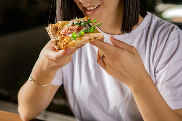 Mujer embarazada sonriendo mientras elige alimentos, simbolizando los antojos en el embarazo con equilibrio nutricional