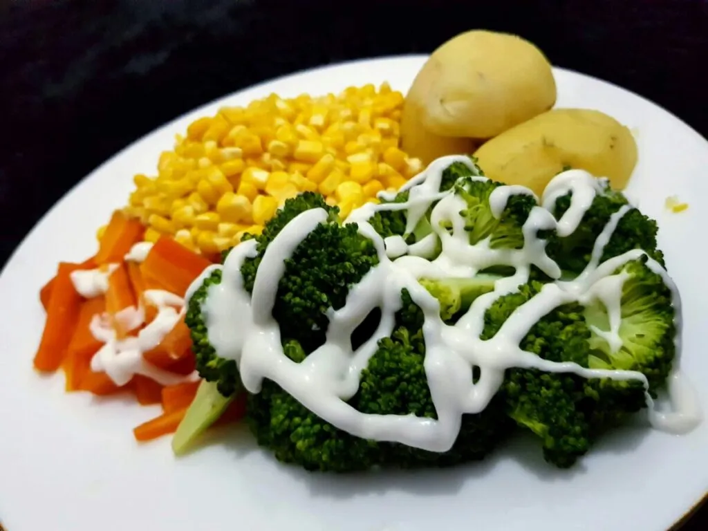 Niños sonrientes comiendo verduras y frutas, representando una alimentación saludable basada en dietas vegetarianas
