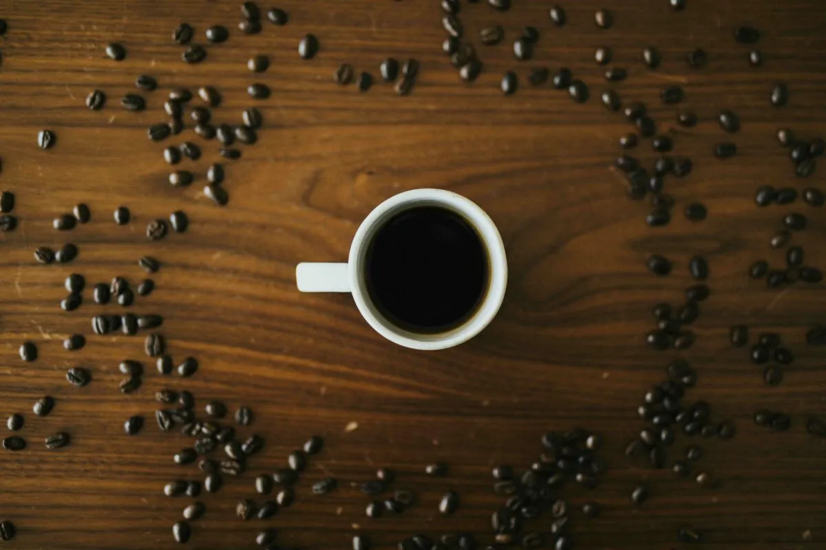 Mujer sonriente bebiendo café sin azúcar en la cocina, reflejando hábitos saludables y bienestar metabólico