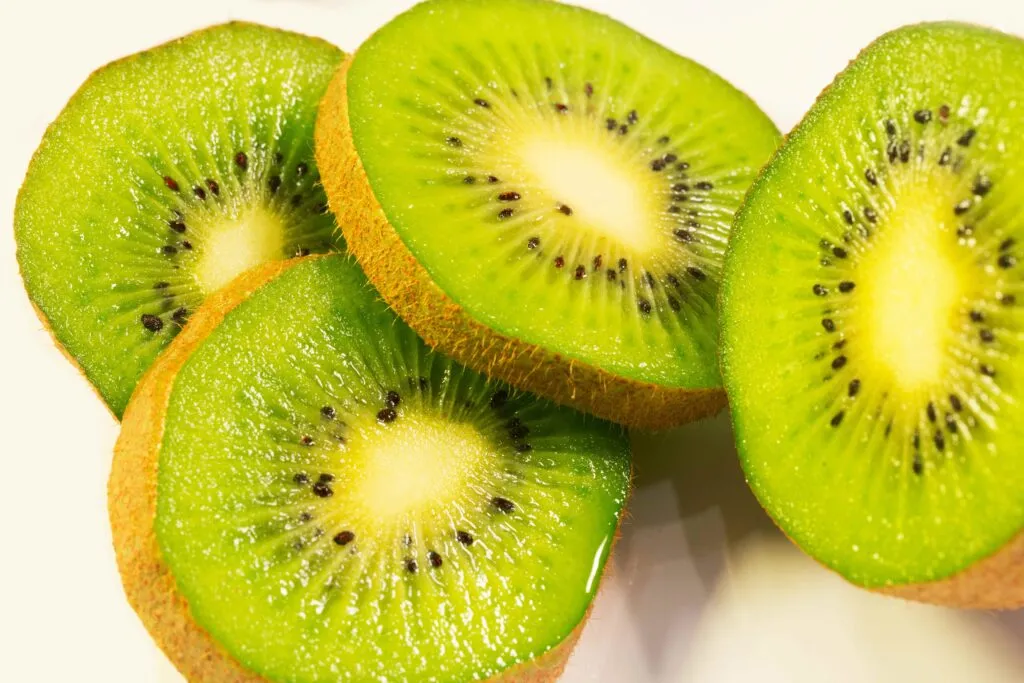 Kiwi partido sobre una mesa con fondo limpio y claro, simbolizando beneficios digestivos y para la piel