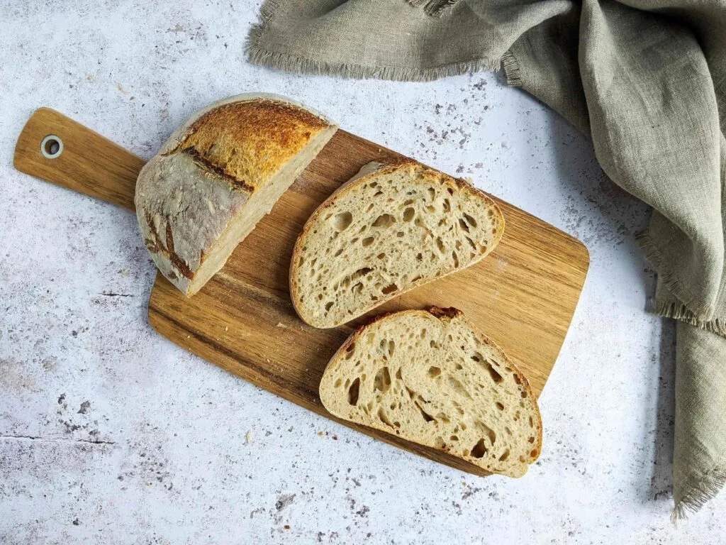 Pan de masa madre recién horneado, sobre tabla de madera, ideal para una dieta saludable y digestiva
