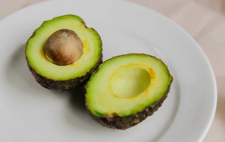 Porción de aguacate cortado acompañado de vegetales como opción saludable de snack nocturno para evitar picoteos.