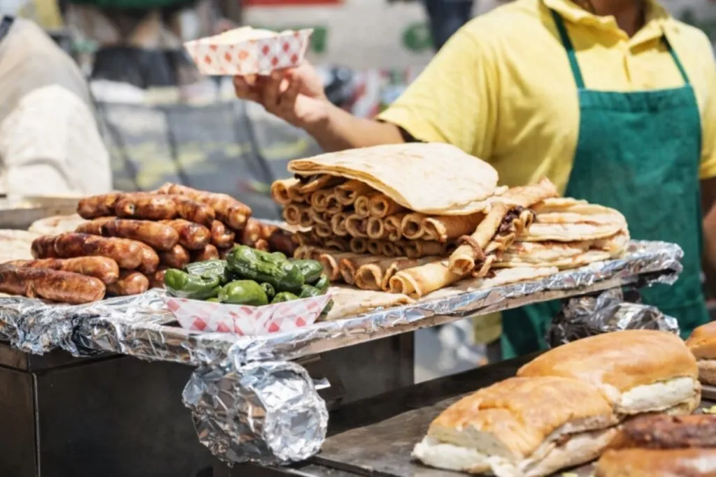 Personas mirando y eligiendo comida callejera en Ciudad de México bajo condiciones de mala calidad del aire en contingencia ambiental