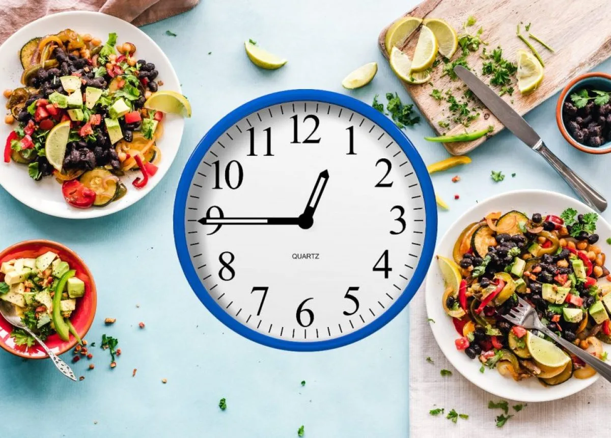 Reloj y alimentos saludables que representan la importancia de respetar horarios de comida para apoyar la salud metabólica