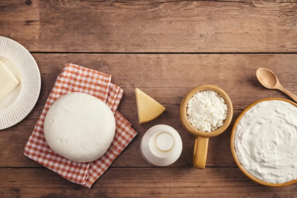 Productos lácteos como leche, queso y yogur en una mesa de madera, ideales para una alimentación saludable