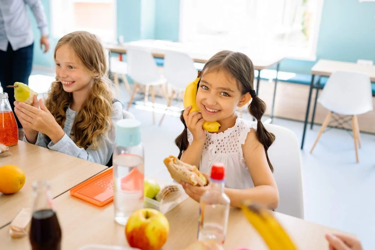 Estudiantes aprendiendo sobre nutrición escolar mientras observan frutas y verduras frescas en un programa educativo escolar.