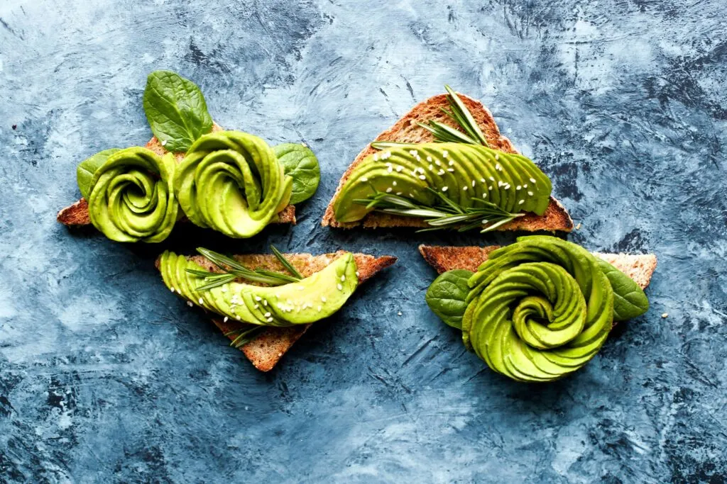 Aguacate fresco partido sobre una tabla de madera, relacionado con los beneficios del aguacate diario para una alimentación saludable.