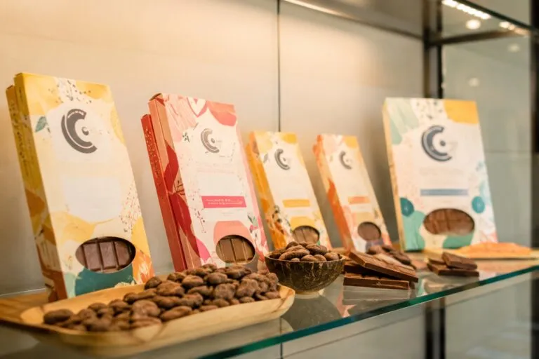 Chocolate artesanal colombiano con cacao de origen presentado en una mesa de madera con granos de cacao y tabletas artesanales.