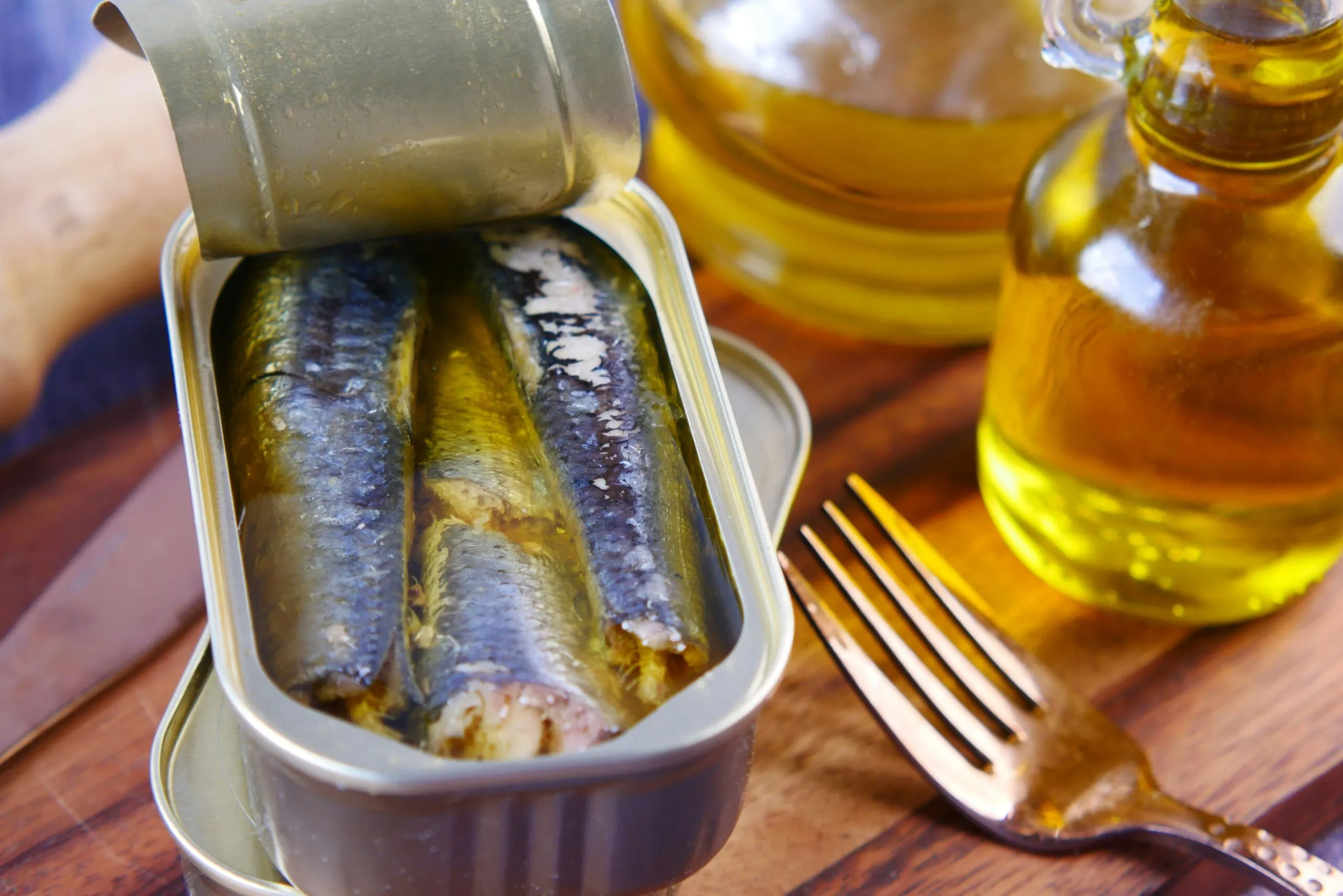 Lata abierta de sardinas acompañada de pan integral, limón y ensalada, representando una alimentación saludable con sardinas en lata.