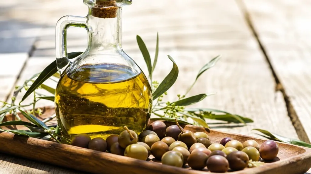 Aceite de oliva virgen extra servido junto a alimentos frescos de la dieta mediterránea