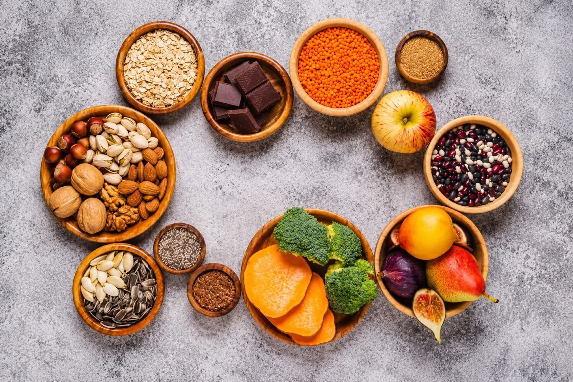 Alimentos con fibra como chía, frijoles, frambuesas y aguacate junto a un tazón de avena