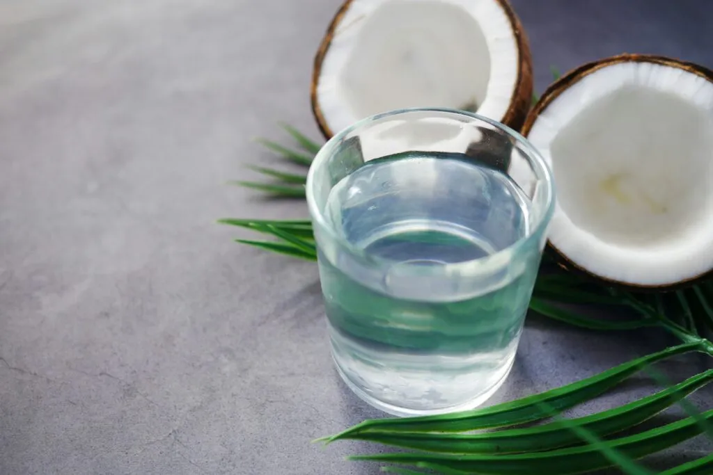 Agua de coco natural servida junto a cocos frescos como alternativa para aportar líquido y minerales.