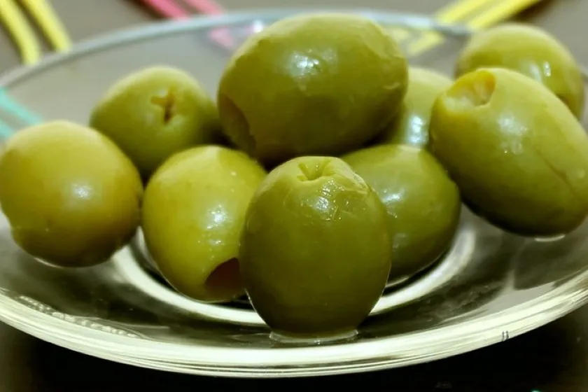 Aceitunas verdes y negras con grasas monoinsaturadas y vitamina E servidas en una porción moderada.
